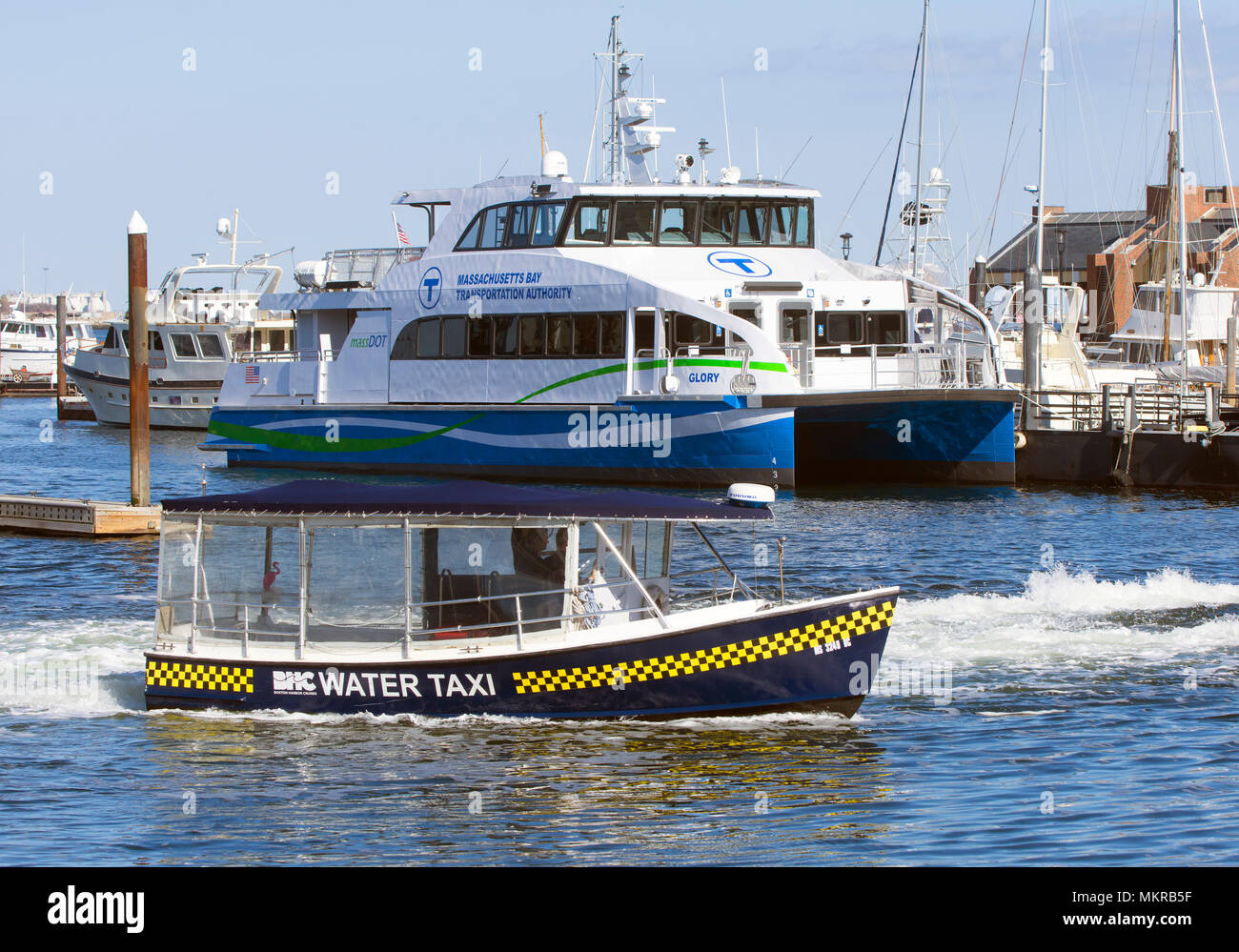 Un taxi d'eau passe un bateau de banlieue dans le port de Boston, Massachusetts, USA Banque D'Images