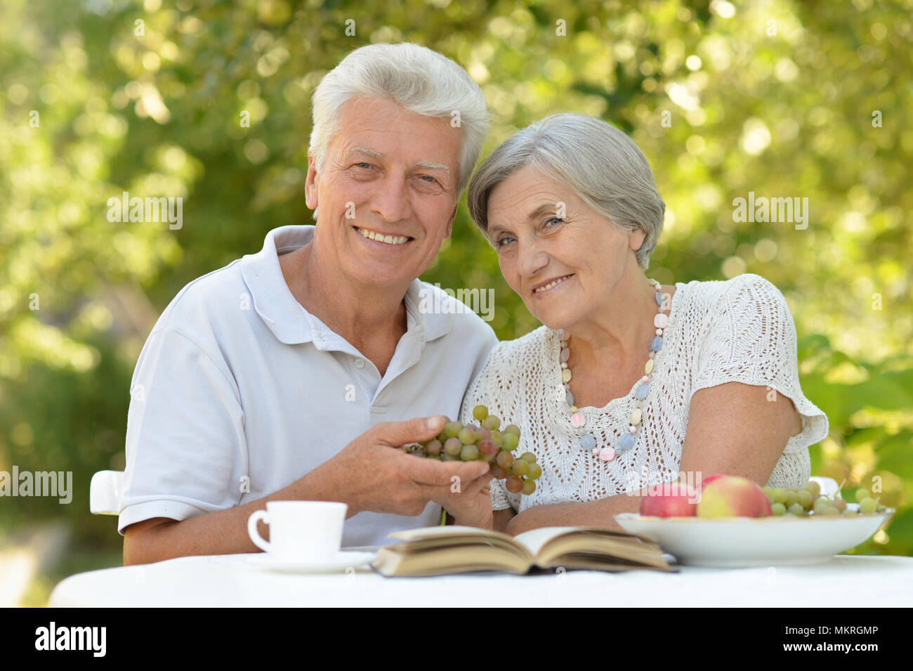 Happy senior couple sitting at table with raisins frais Banque D'Images