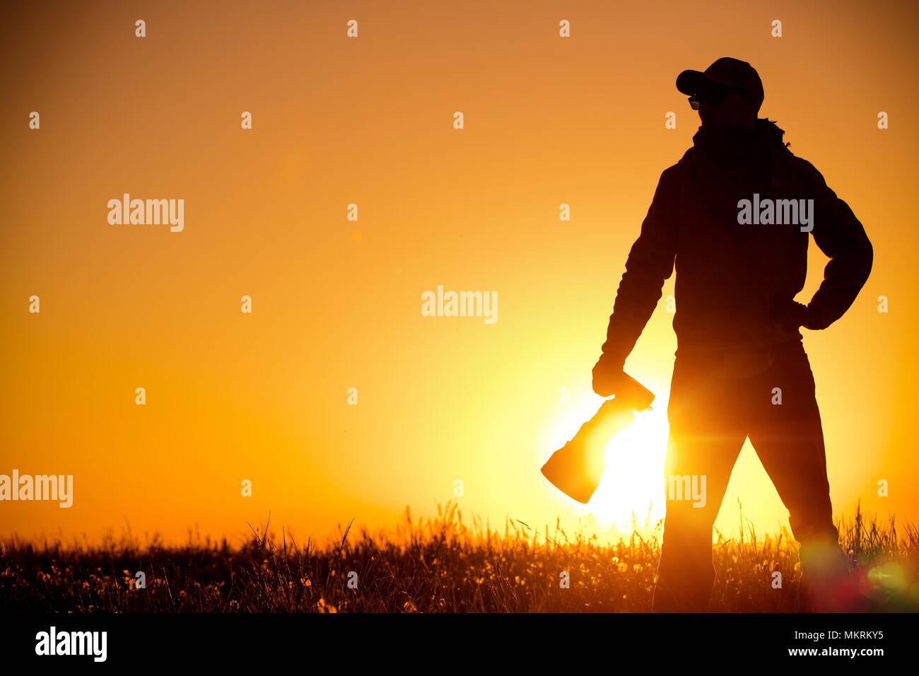 Photographe en plein air équipée d'un grand téléobjectif dans l'emplacement distant pendant le coucher du soleil magnifique. Banque D'Images