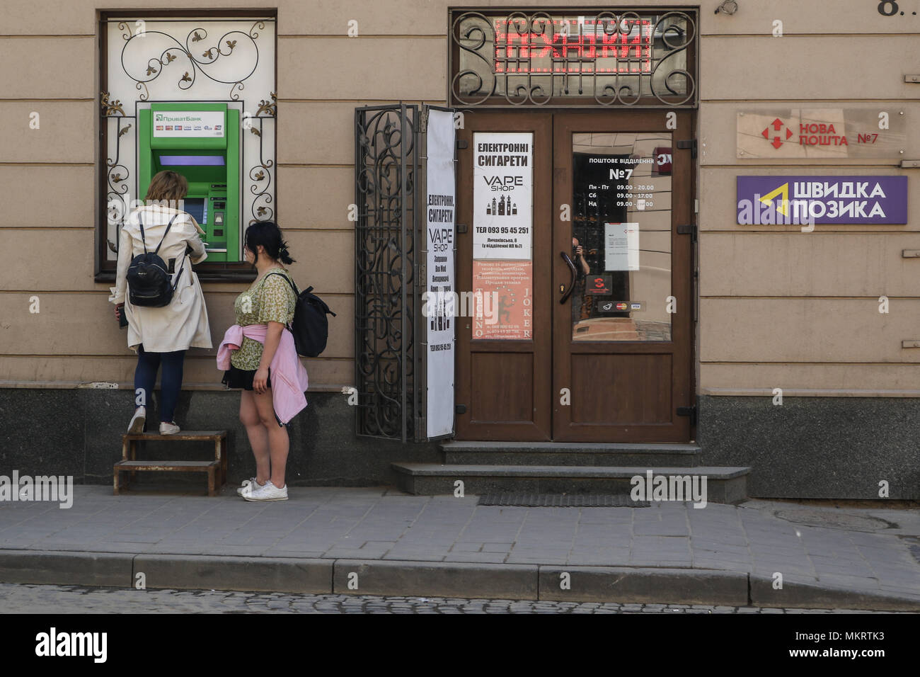 Deux femmes qui se retirer de l'argent d'un Privat Bank (banque privée) distributeur automatique sont considérés à Lviv, Ukraine le 30 avril 2018 © Vadim Pacajev / Alamy Live News Banque D'Images