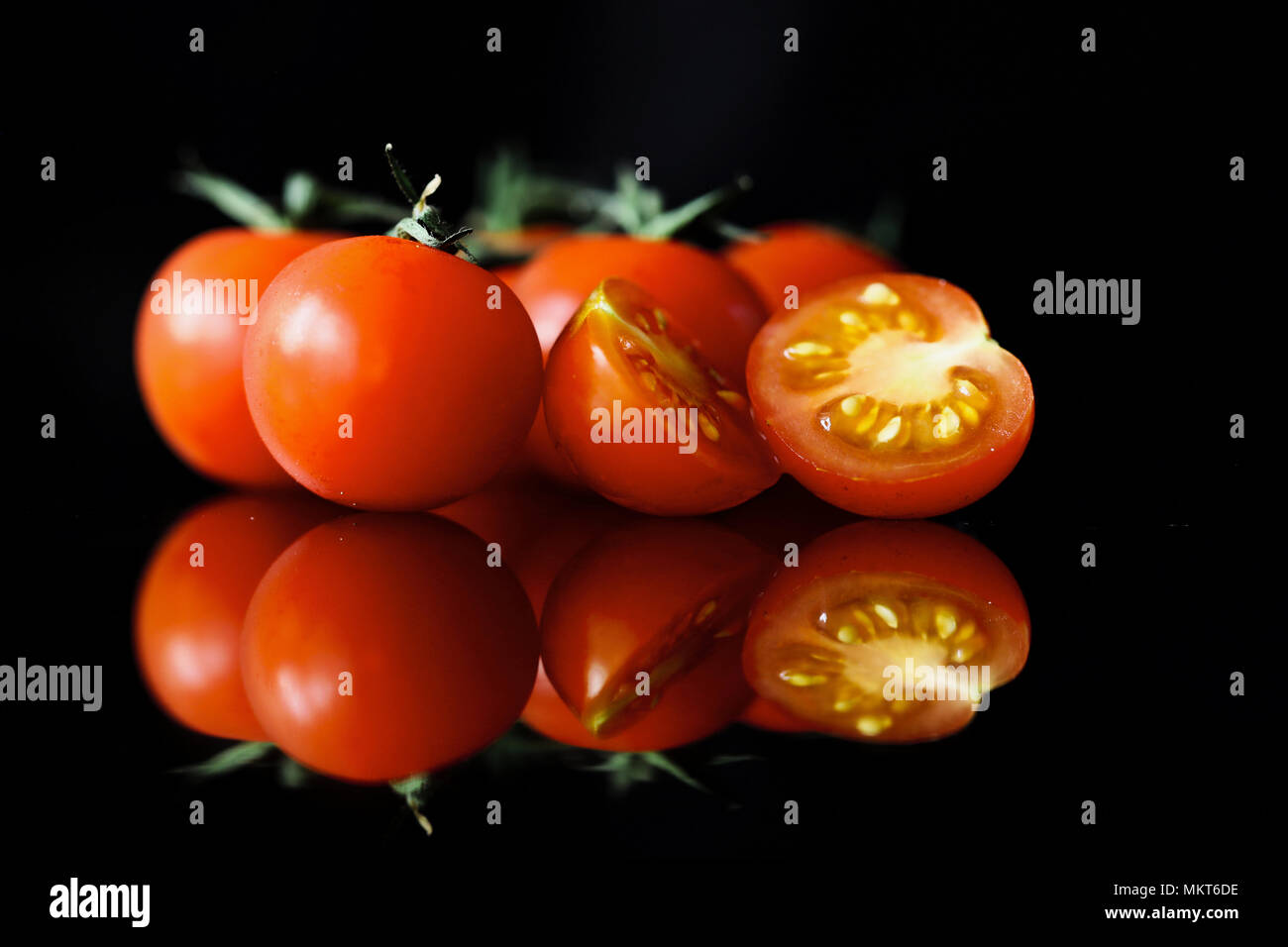 Tomates cerises reflétée sur la vigne sur un fond noir Banque D'Images
