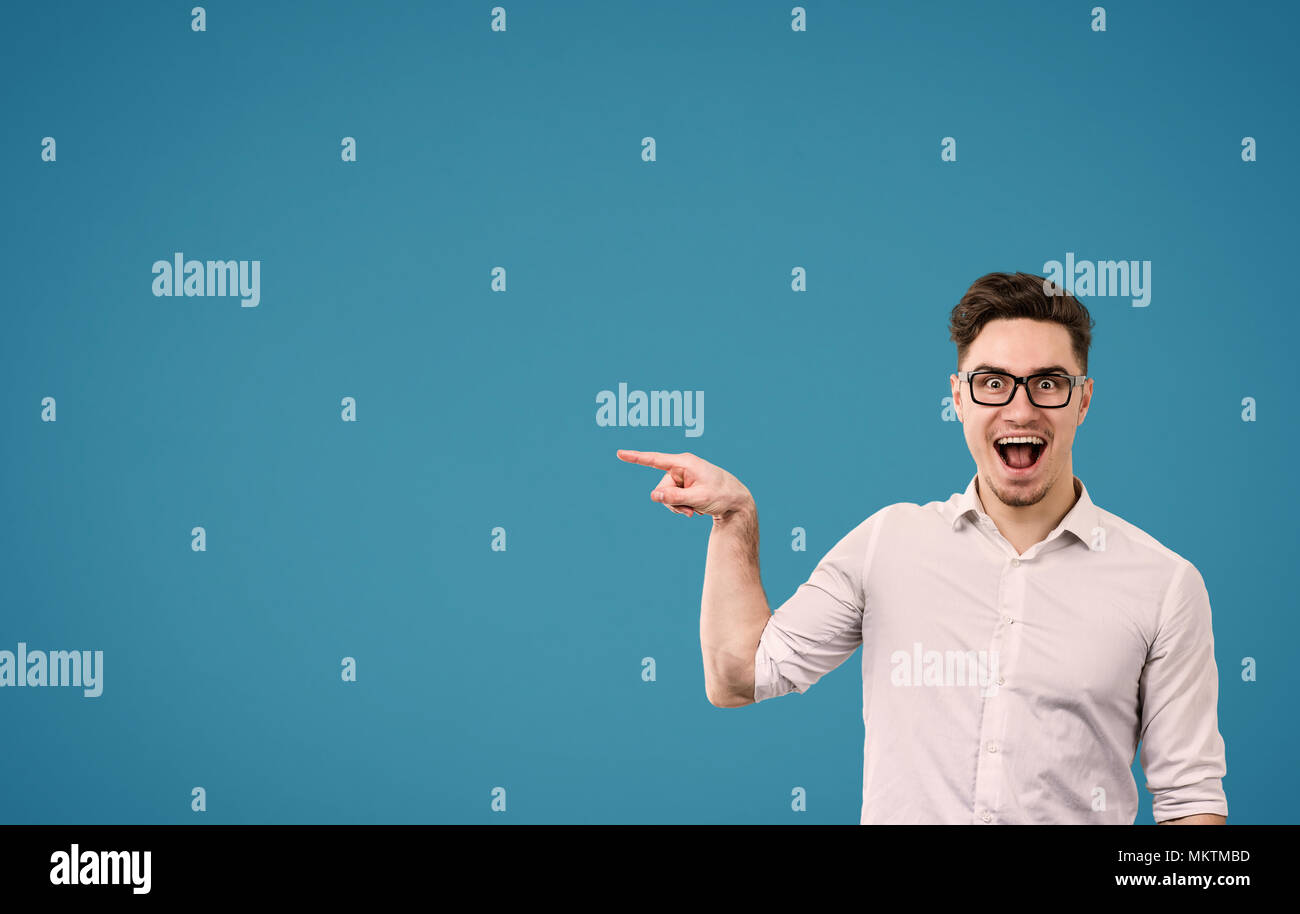 Jeune homme hipster dans les verres en soulignant l'écart joyeusement sur fond bleu Banque D'Images