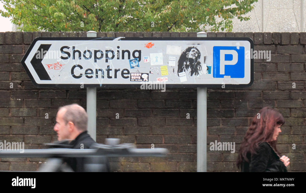 Parking centre commercial signe avec l'homme et la femme se déplaçant dans différentes directions rasta Bob Marley graffitti Banque D'Images