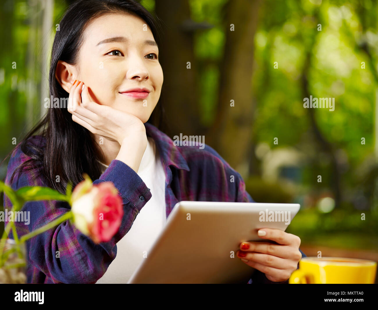Beautiful young asian woman using digital tablet en buvant un cappuccino au café. Banque D'Images