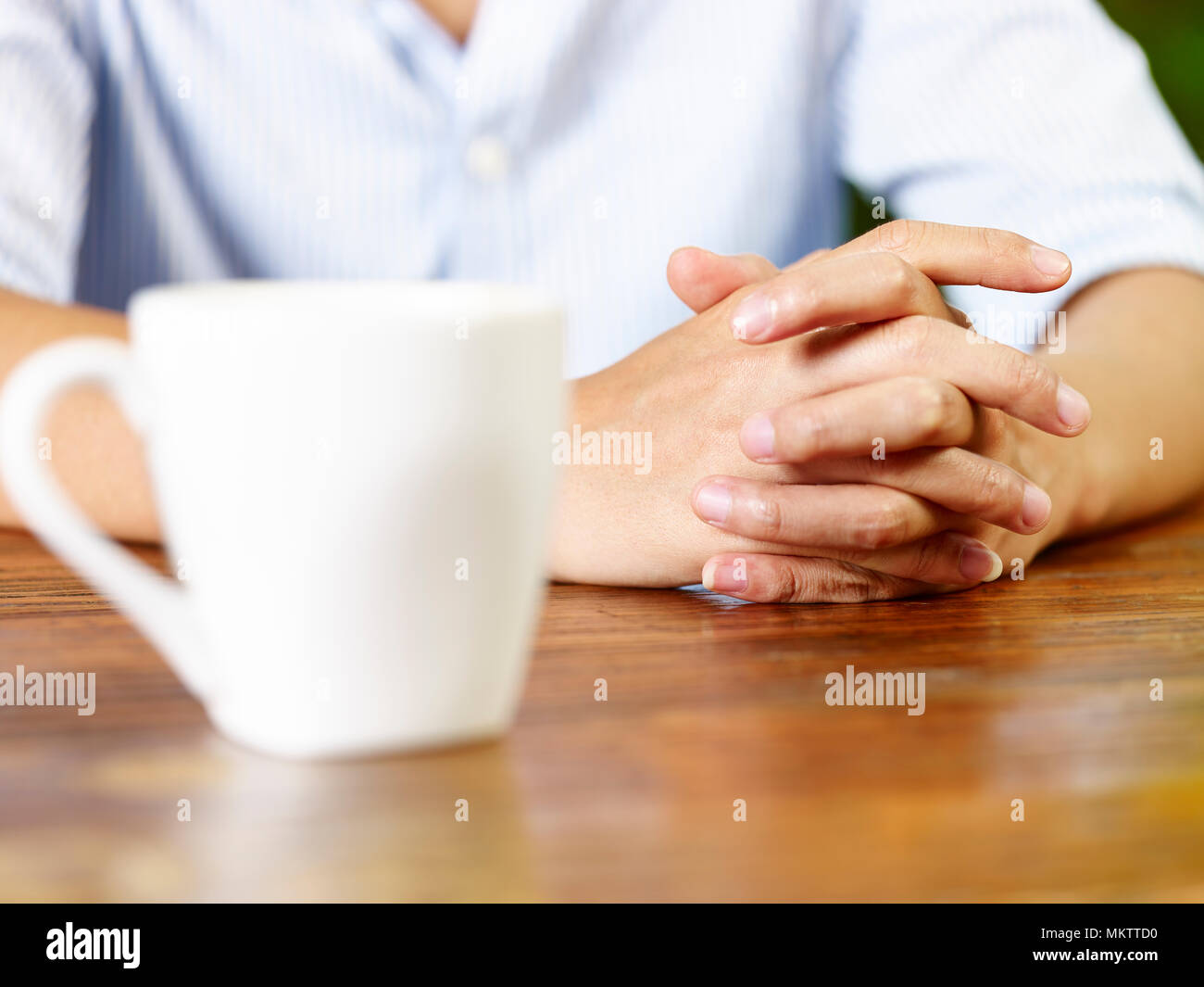 Mains d'un jeune homme et un mug blanc sur table en bois dans la région de café ou de thé. Banque D'Images