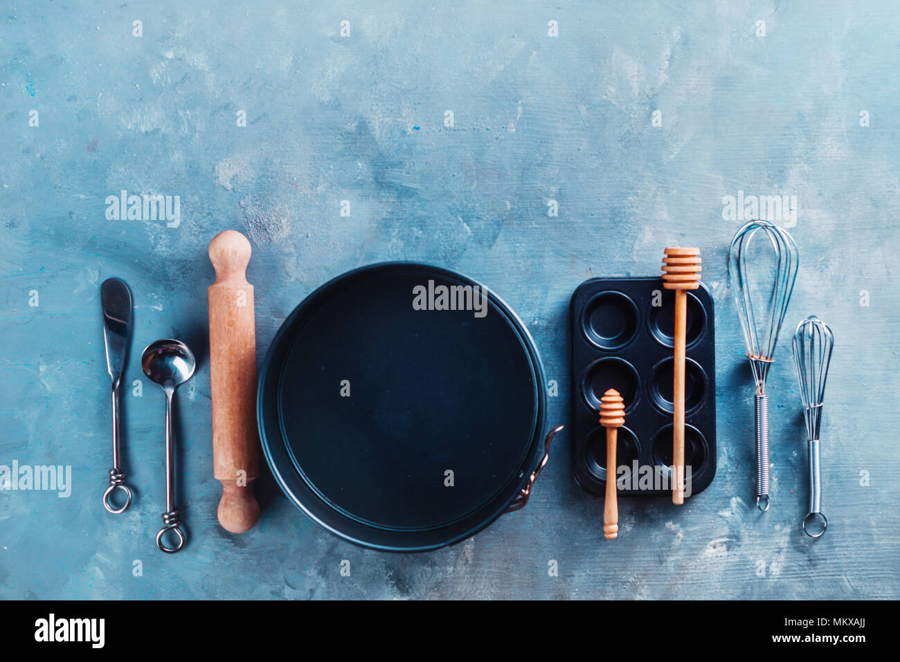 Formes de cuisson et un muffin tin avec fouets, cuillères, de farine, de sucre et d'épices sur une table de cuisine en marbre. Outils de cuisson et les ingrédients avec copie espace. Ce concept de pâtisserie. Banque D'Images