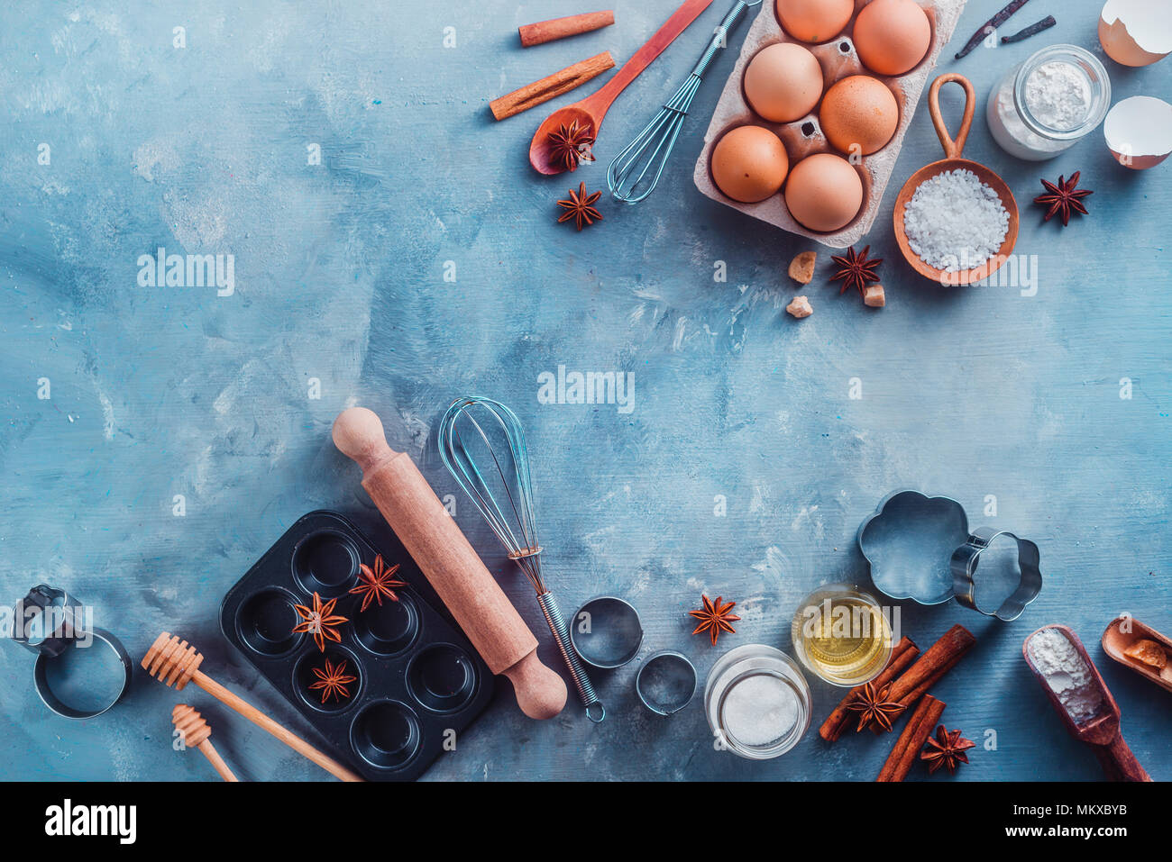 Faire de la pâtisserie avec mise à plat, pelles, fouets, emporte-pièce, muffin tin, le sucre, la farine, les oeufs, l'anis étoile et la cannelle sur une table en béton avec copie espace. Outils de cuisson et les ingrédients d'en haut Banque D'Images