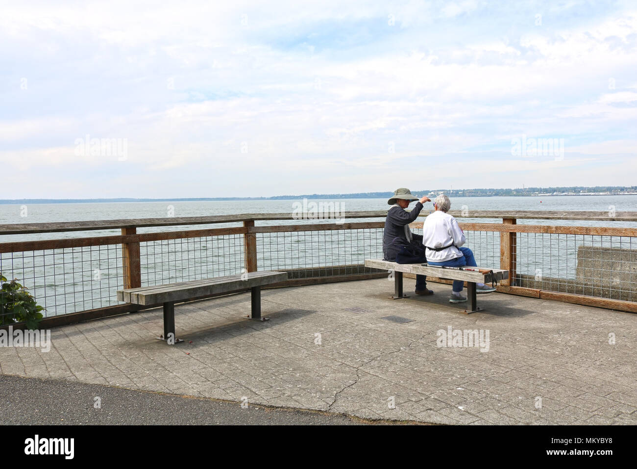 Deux femmes âgées assis sur un banc près de la rambarde au Boulevard Park à Bellingham, WA, USA. Banque D'Images