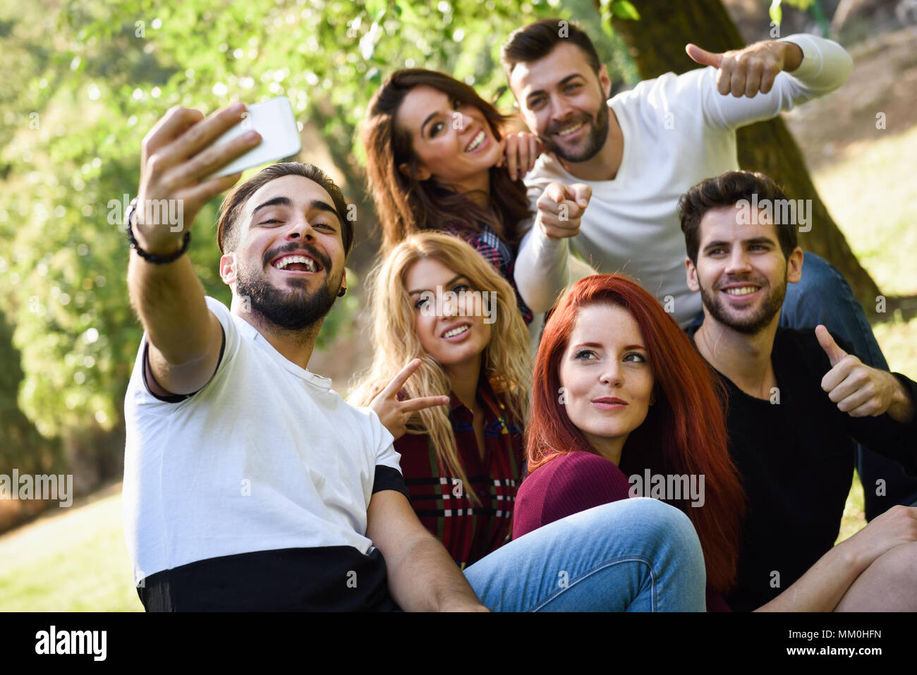 Groupe d'amis prenant en selfies parc urbain. Cinq jeunes gens portant des vêtements décontractés. Banque D'Images