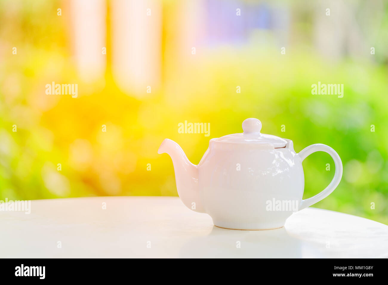 Théière sur un arrière-plan flou de la nature durant le petit-déjeuner dans la lumière du soleil du matin Banque D'Images