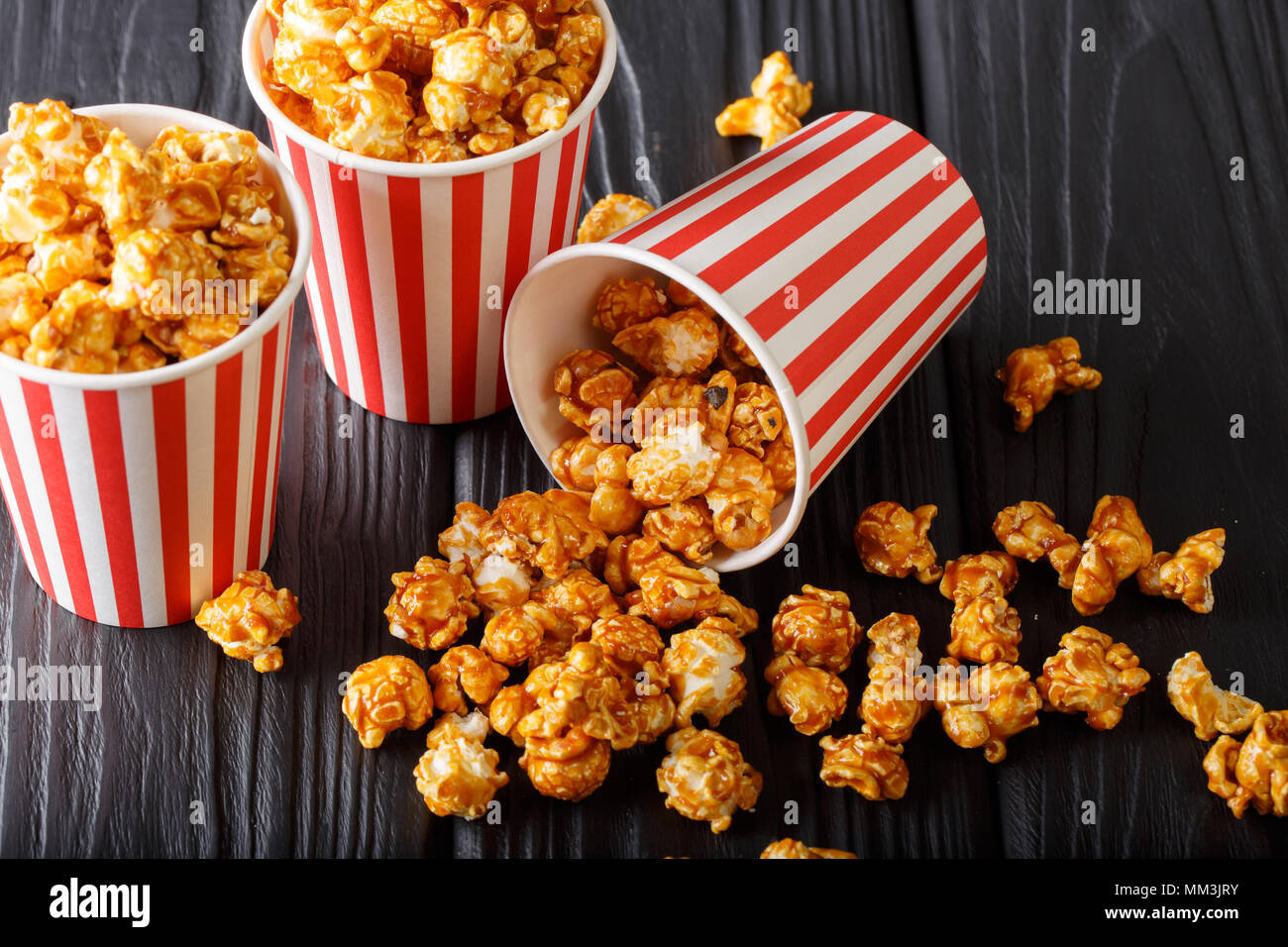 Délicieux avec du pop-corn caramel dans la benne Papier sur table en bois sur un fond sombre horizontale. Banque D'Images