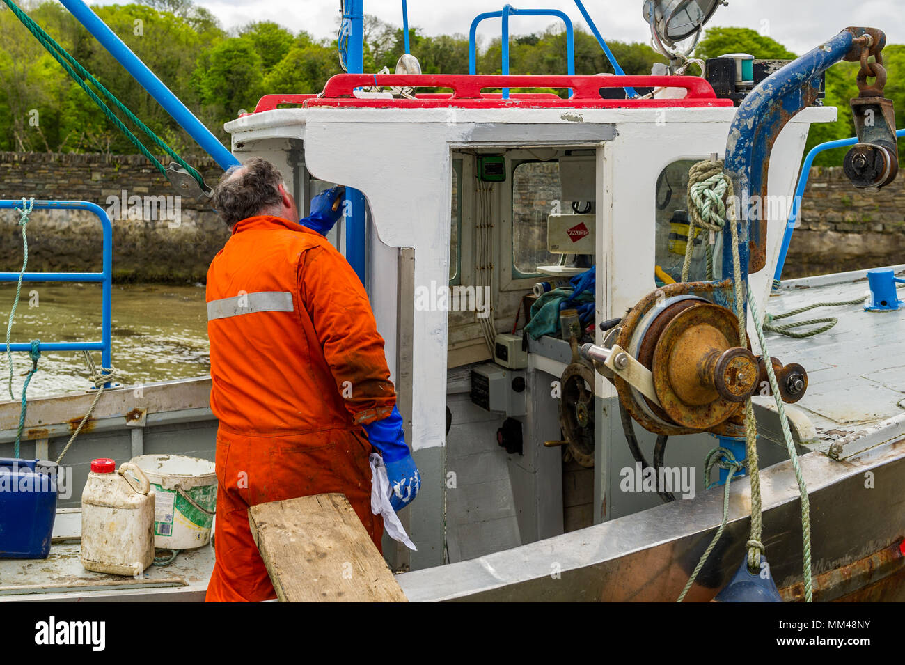 Pêcheur peint son voile qui est liée à une rampe à Bantry, dans le comté de Cork, Irlande. Banque D'Images