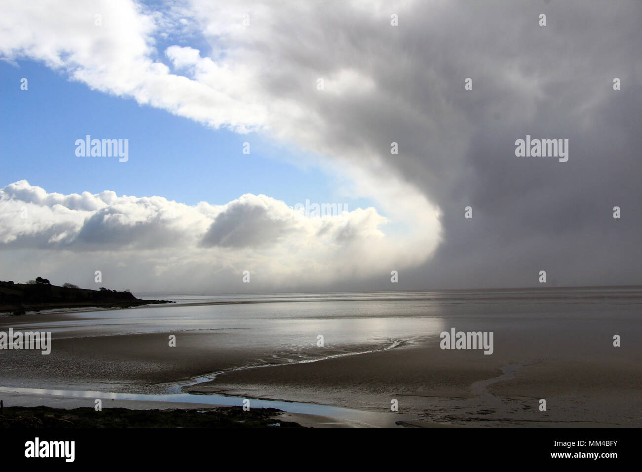 La formation de nuages de tempête spectaculaire contre le ciel bleu sur la baie de Morecambe à marée basse Banque D'Images