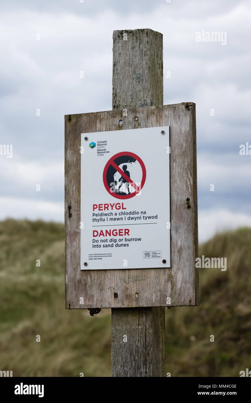 Inscrivez-avertissement ne pas creuser ou s'enfouissent dans les dunes de sable en raison du danger d'effondrement posté par Ressources naturelles du pays de Galles sur Harlech beach dans le Nord du Pays de Galles Banque D'Images