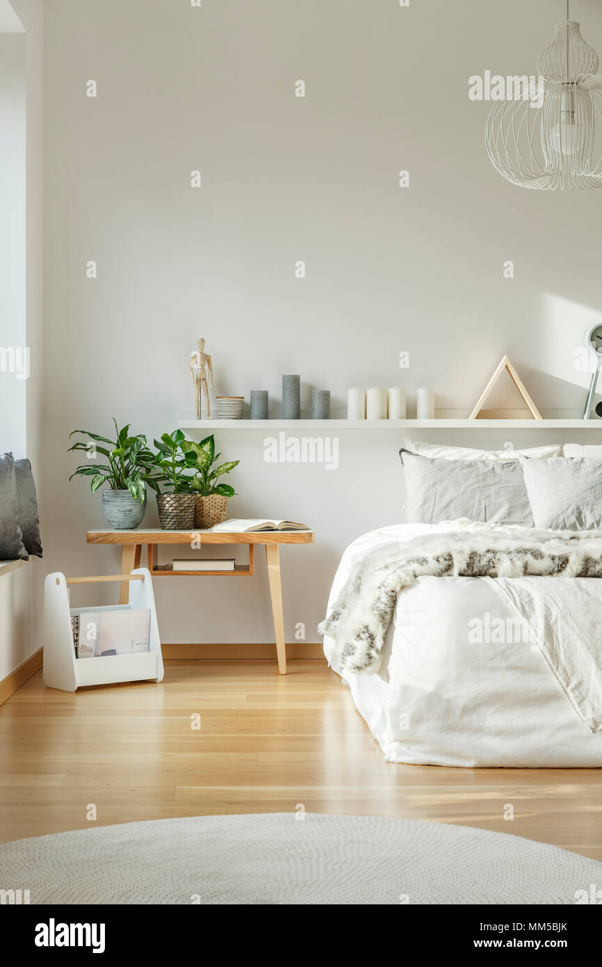 Intérieur confortable chambre blanche avec un lit king-size, un tapis, des ornements et de sol en bois Banque D'Images