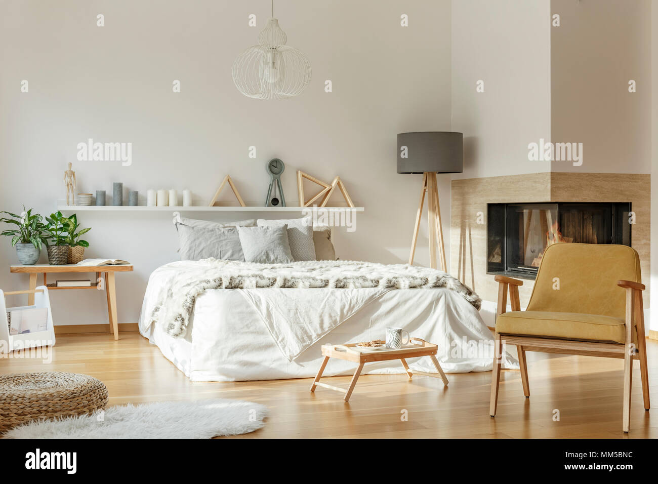 Intérieur chambre confortable avec cheminée, un lit king-size, un tapis, chaise, lampe, ornements et plancher en bois Banque D'Images