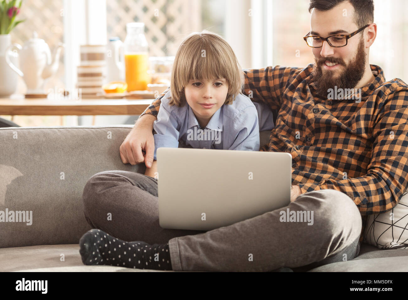 Heureux père et fils de regarder un film sur un ordinateur portable, assis sur un canapé à la maison Banque D'Images
