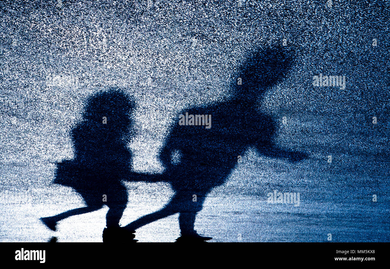 Silhouette d'ombre floue flou artistique young couple holding hands en marchant sur la route d'asphalte dans la nuit Banque D'Images