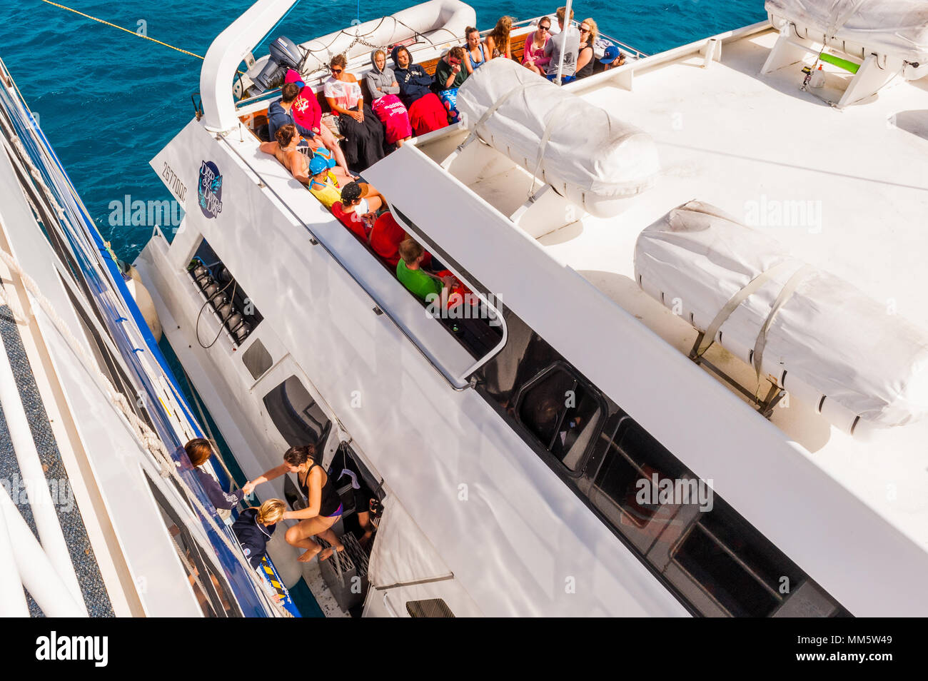 Passagers et produits sont transférés d'un bateau de plongée à un autre milieu de l'océan au-dessus de la Grande Barrière de Corail, Queensland, Australie. Banque D'Images