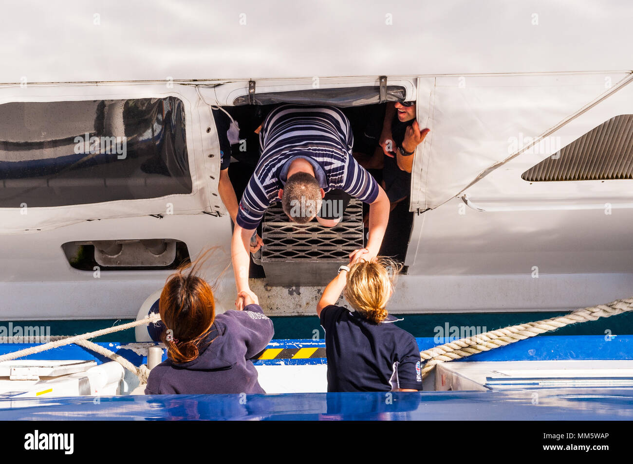 Passagers et produits sont transférés d'un bateau de plongée à un autre milieu de l'océan au-dessus de la Grande Barrière de Corail, Queensland, Australie. Banque D'Images