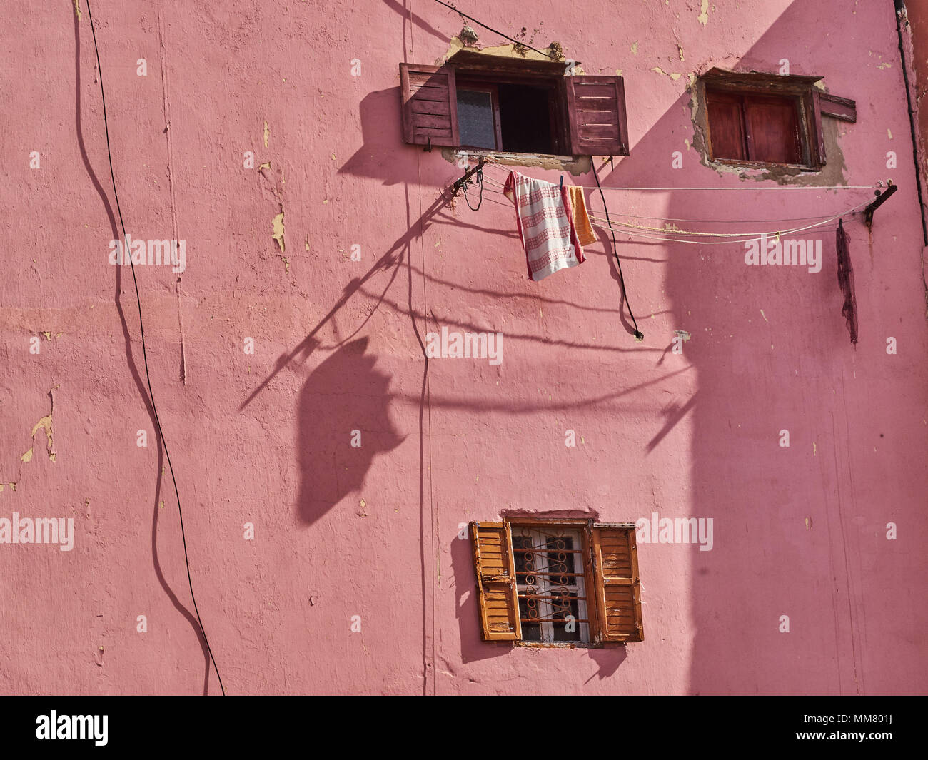 Mur de la chambre rose avec de petites fenêtres en bois décoratifs et des vêtements accrochés sur la corde. Banque D'Images