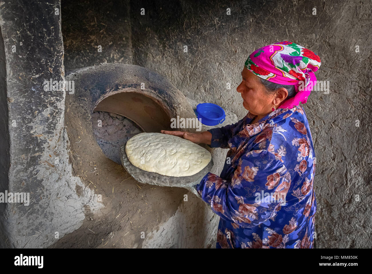 Boukhara, Ouzbékistan - 20 Avril 2018 : une femme âgée se prépare à mettre la galette dans le tandoor - un four ouzbek traditionnel Banque D'Images