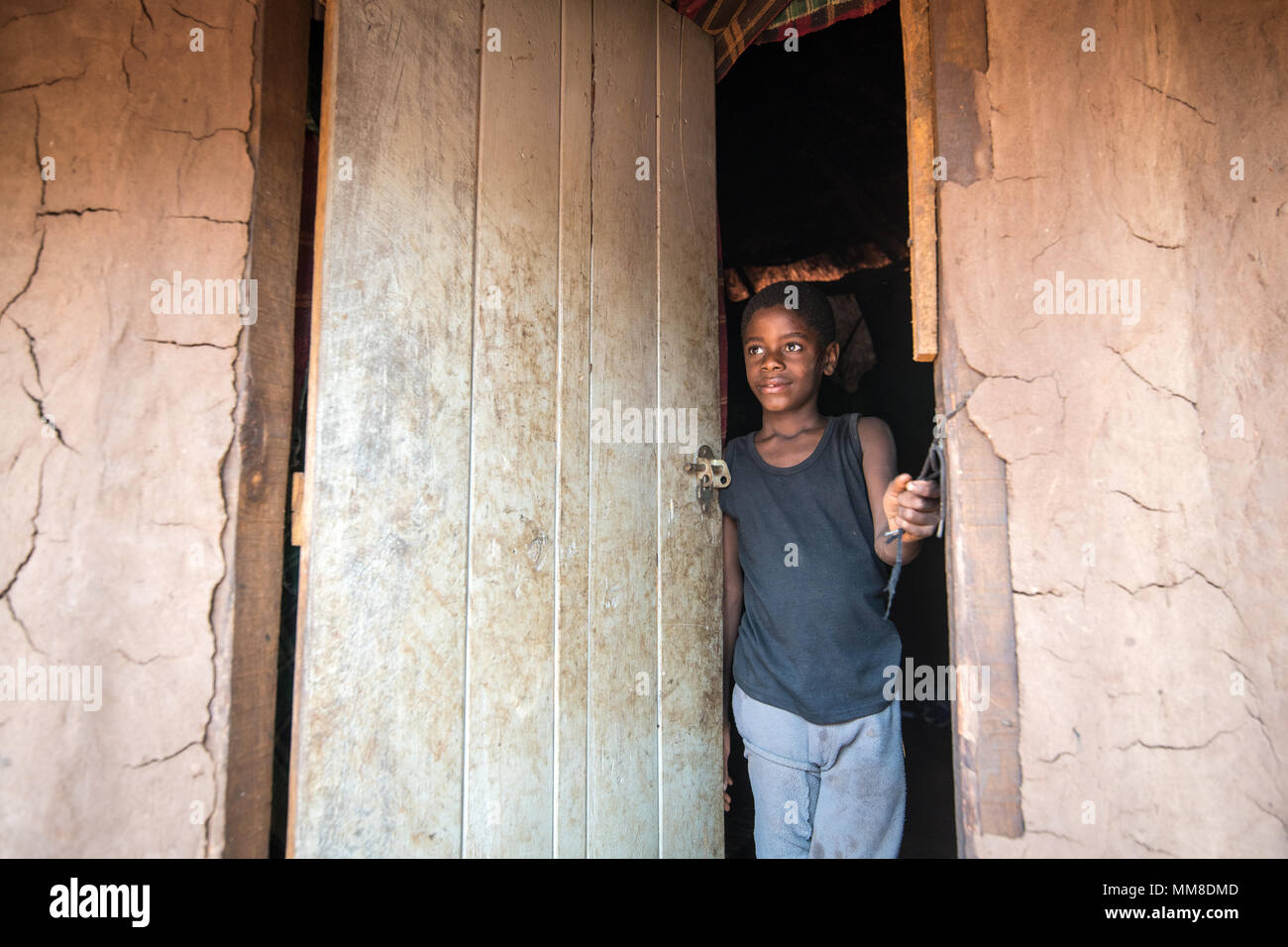 Jeune garçon zambien se trouve dans la porte de la hutte sur le loquet de porte, Mukuni Village, Zambie Banque D'Images