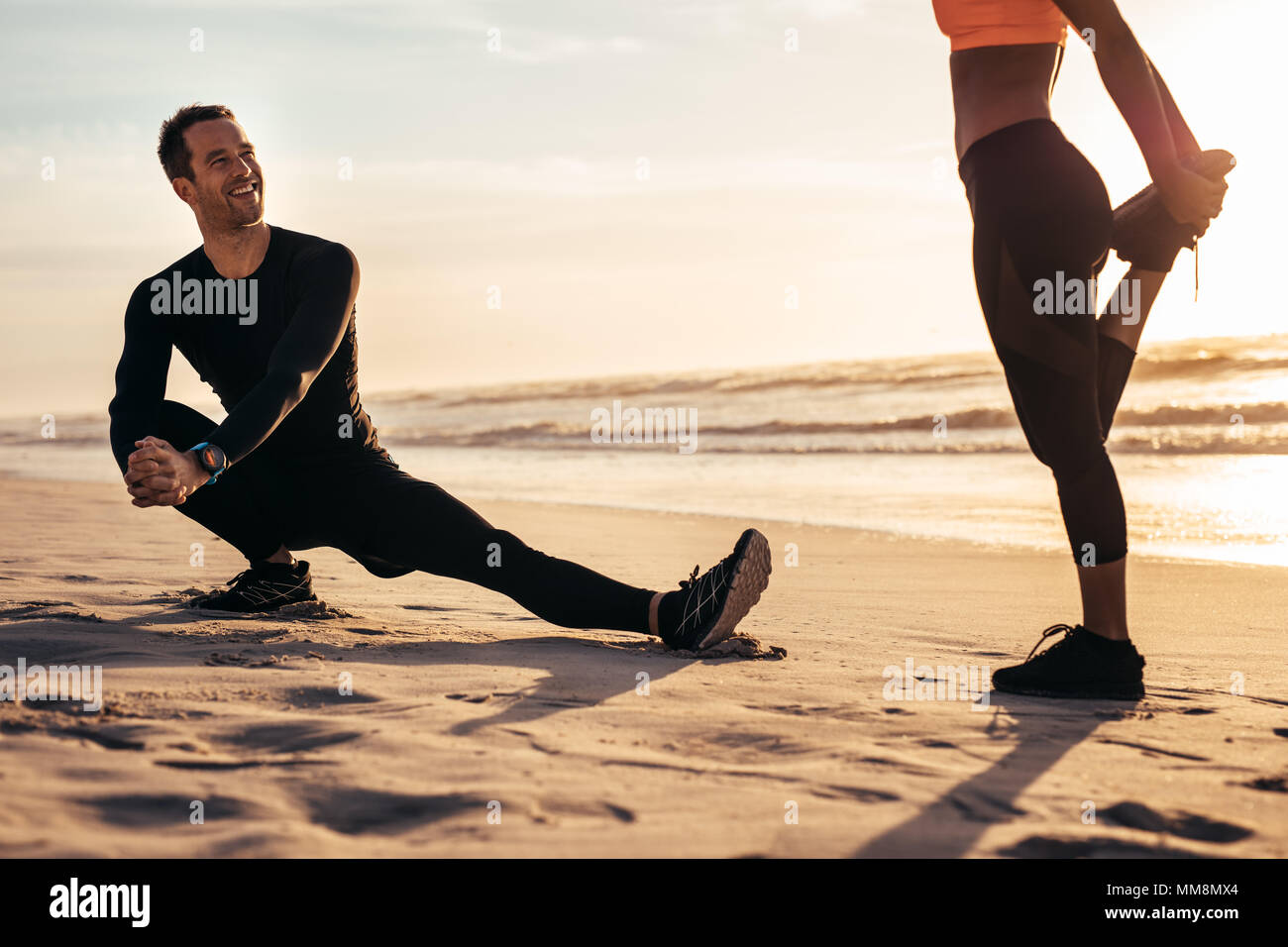 Les jeunes l'exercice sur la plage de matin. Runner stretching et réchauffe le long de la mer et d'avoir un chat. Banque D'Images
