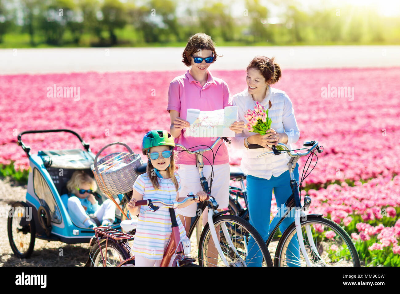 Heureux famille néerlandaise riding bicycle in tulip champs de fleurs en Hollande. Mère et enfants sur des vélos à la floraison des tulipes en Hollande. Bébé en vélo. Banque D'Images