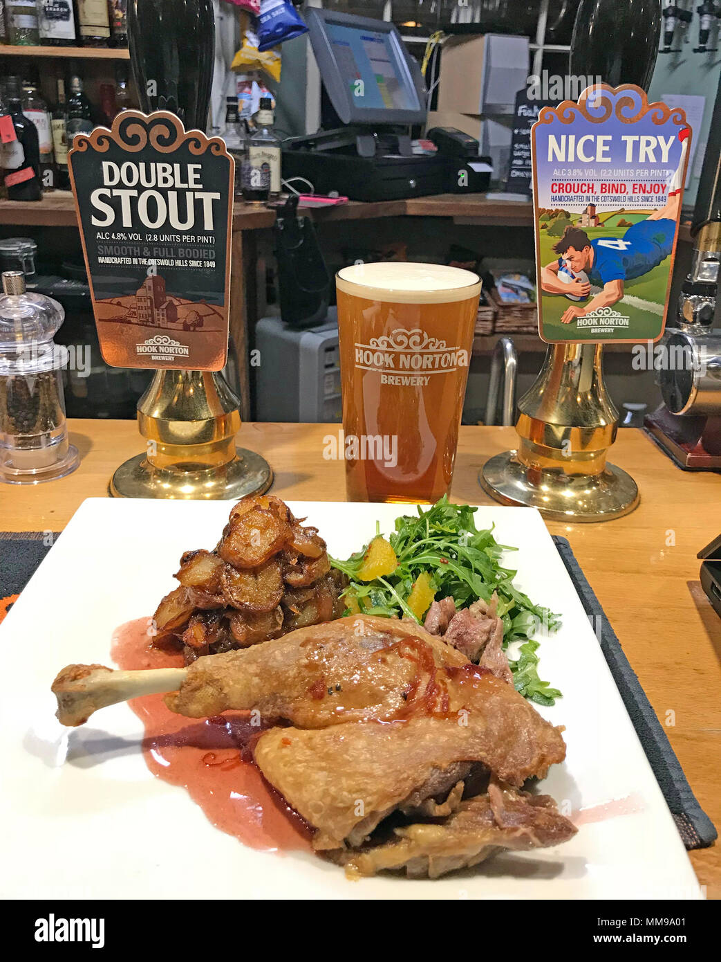Bar nourriture, cuisse de canard, sauce à l'orange, avec de la bière les pompes sur un bar, dans un pub anglais traditionnel, England, UK Banque D'Images