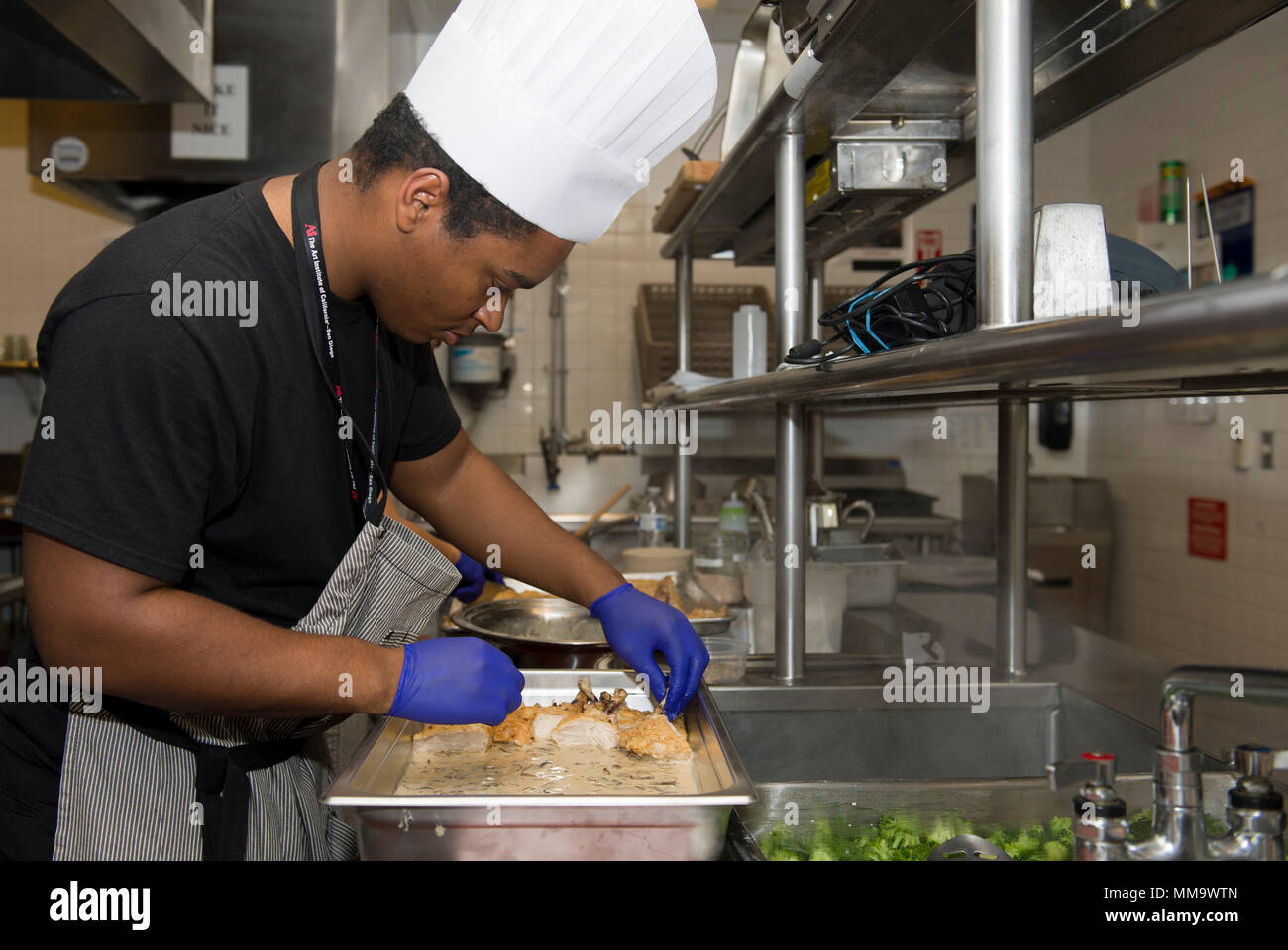 SAN DIEGO, Californie (sept. 22, 2017) 2ème classe spécialiste culinaire Cordarro Newton, affecté à la Naval Air Facility (NAF) Atsugi, au Japon, les lieux poulet sur un plateau de service à l'Art Institute de Californie à San Diego. Newton et neuf autres spécialistes culinaires (CS) est diplômé de la Marine Cours de formation culinaire avancé CS où ils ont reçu plus de 800 heures de formation culinaire avec quatre chefs certifiés. (U.S. Photo par marine Spécialiste de la communication de masse/Morenogarcia Matelot Jasen) Parution Banque D'Images