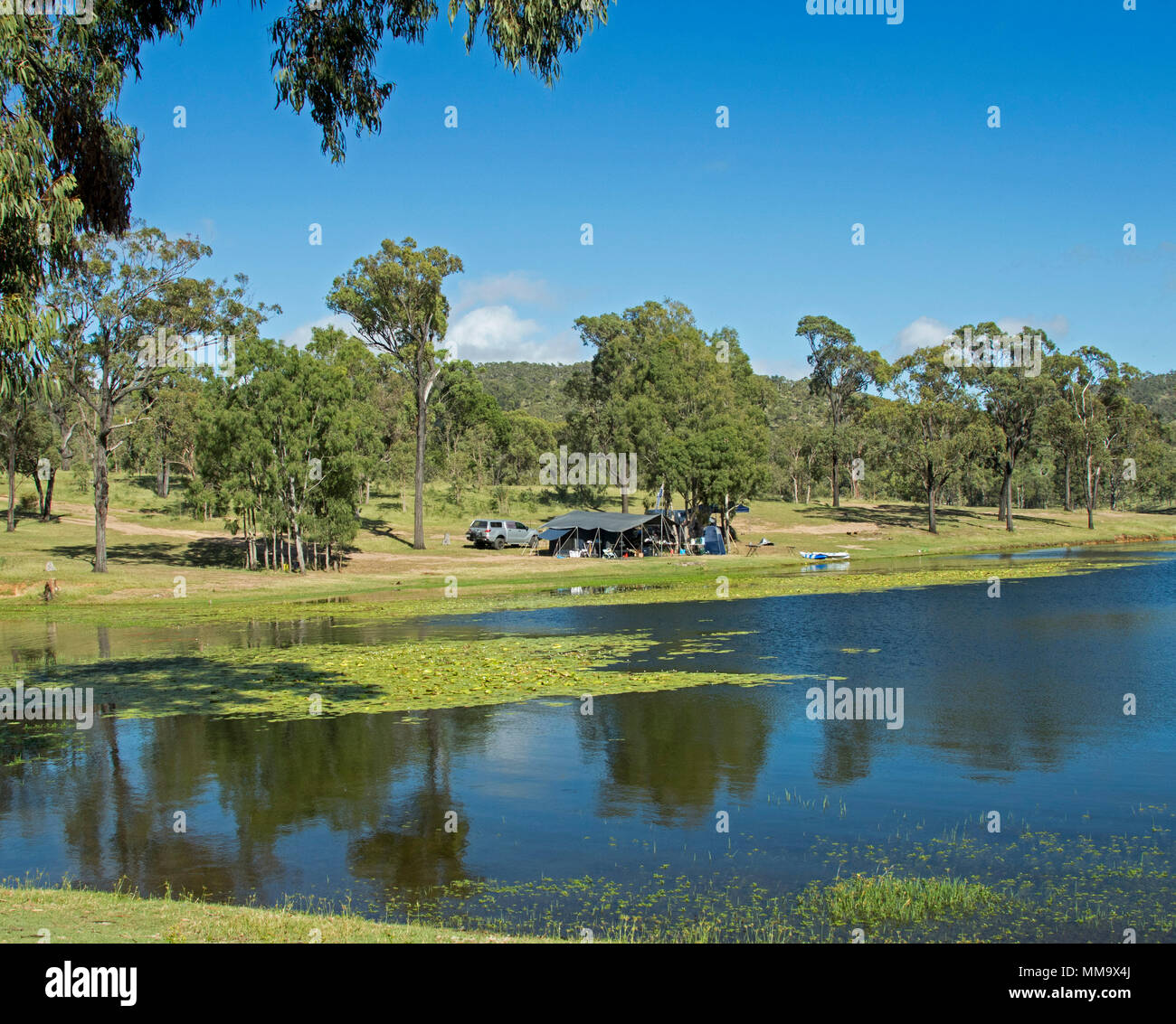 Les campeurs avec une tente et une voiture dans un paysage boisé qui se reflète dans les eaux calmes du lac bleu sous ciel bleu à Eungalla Australie barrage Banque D'Images