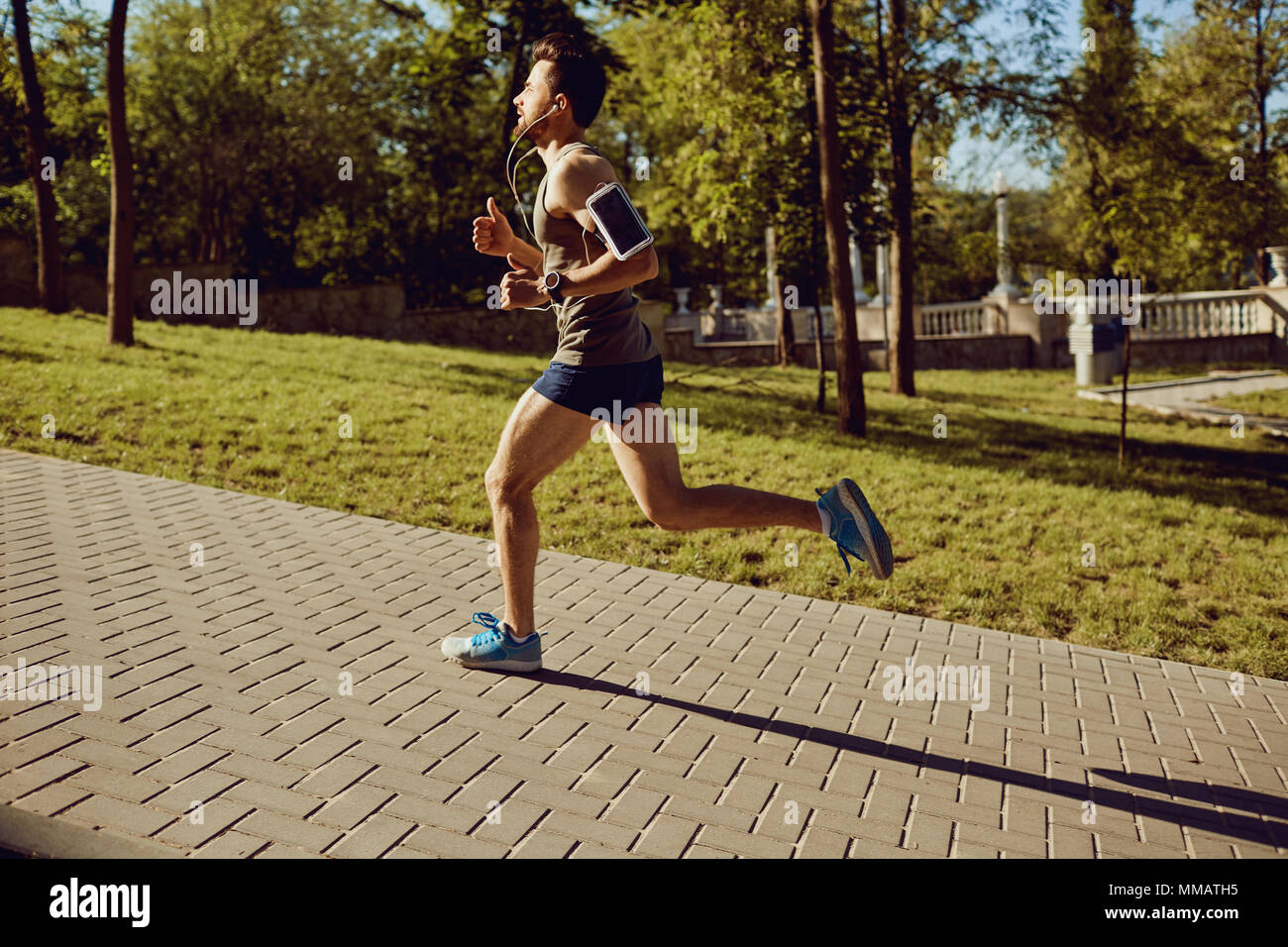Un homme runner exécute le long de la route pour le parc. Banque D'Images