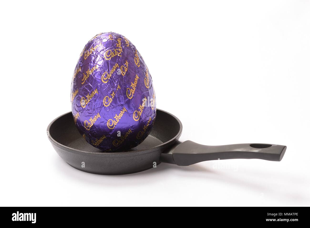 Concept de droit d'un grand Cadbury's easter egg dans une petite poêle sur un fond blanc. Banque D'Images