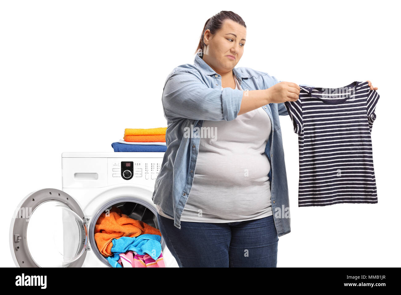 Triste l'embonpoint woman holding a rapetissé shirt en face d'un lave-linge isolé sur fond blanc Banque D'Images