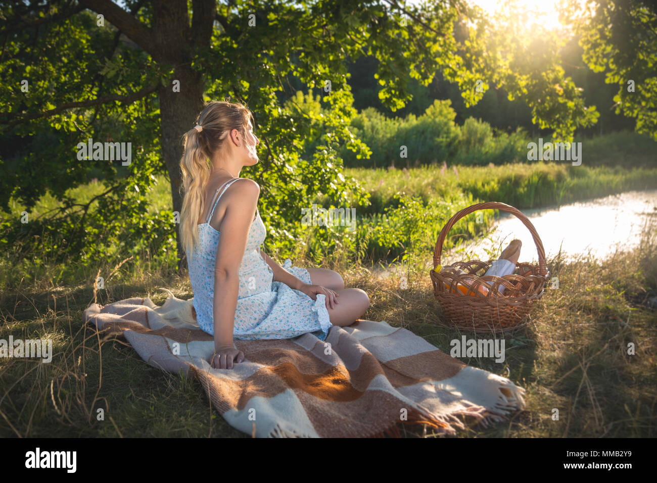 Image aux couleurs de belle jeune femme avoir pique-nique sous grand arbre à au soleil du soir sur le lac Banque D'Images
