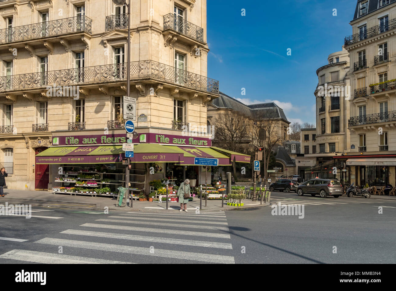 Une femme en attente à un passage pour piétons à l'extérieur de l'ile aux fleurs l'île aux fleurs ou de traverser la rue des Écoles, Paris, France Banque D'Images