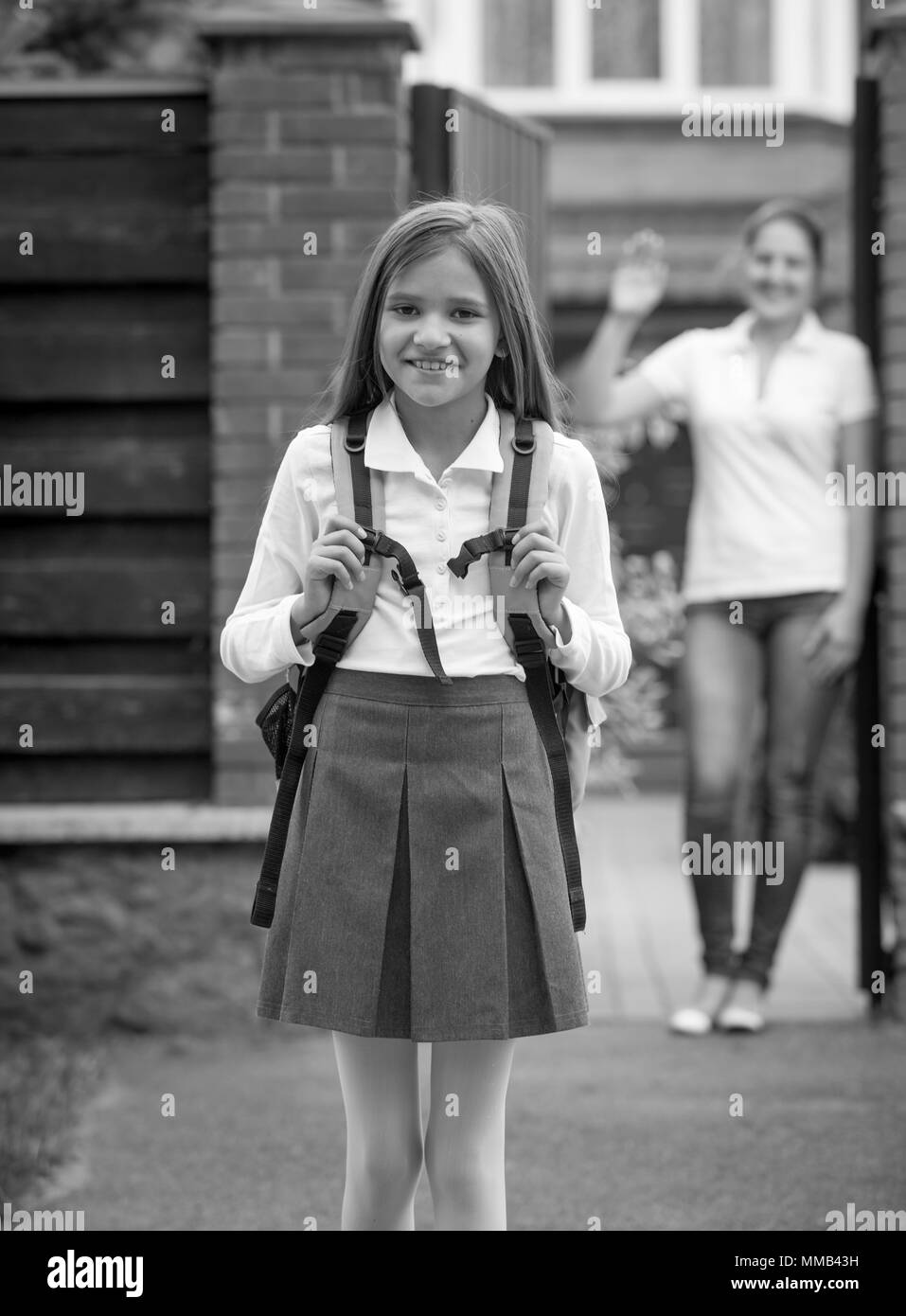 Le noir et blanc portrait of smiling girl in school uniform posing in front of house Banque D'Images
