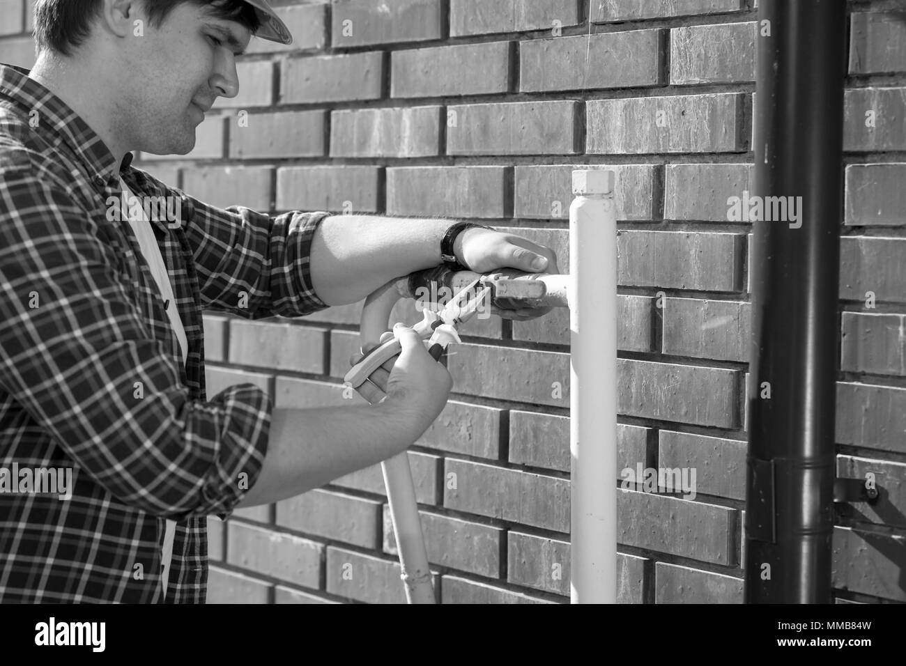 Image en noir et blanc gros plan du travailleur masculin la réparation de la valve à gaz avec une pince Banque D'Images