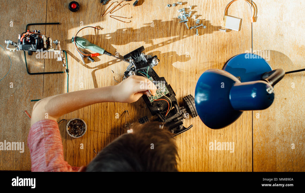 Vue de dessus d'un enfant faisant une voiture robot à la maison. High angle view of a Boy travaille sur son projet électronique. Banque D'Images
