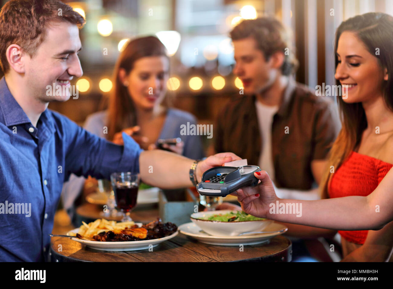 Groupe d'Amis de payer pour repas au restaurant Banque D'Images