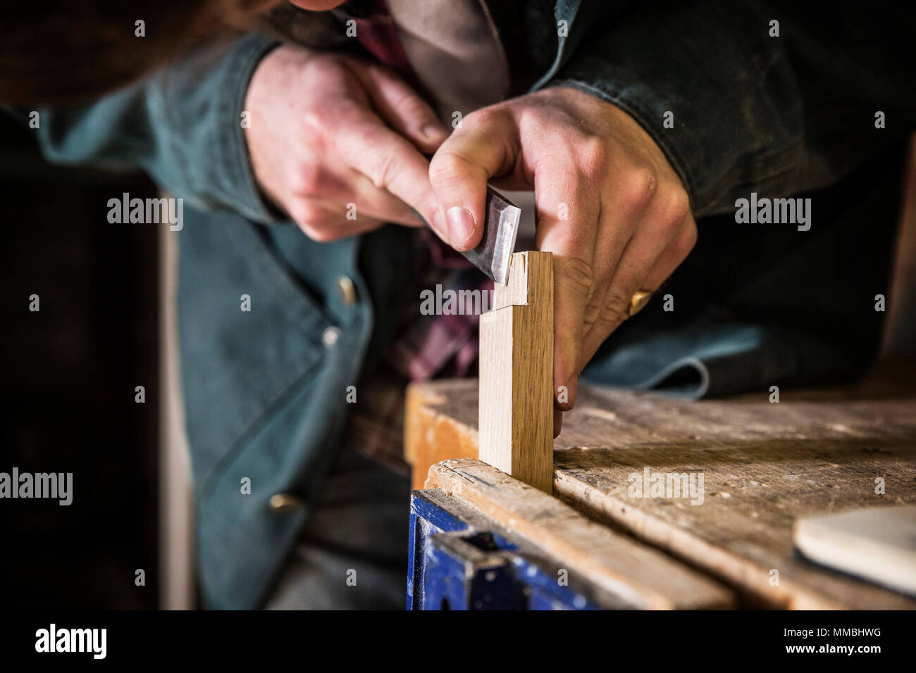 Portrait de l'homme travailler debout dans un atelier de travail du bois, à l'aide d'un burin sur le morceau de bois. Banque D'Images