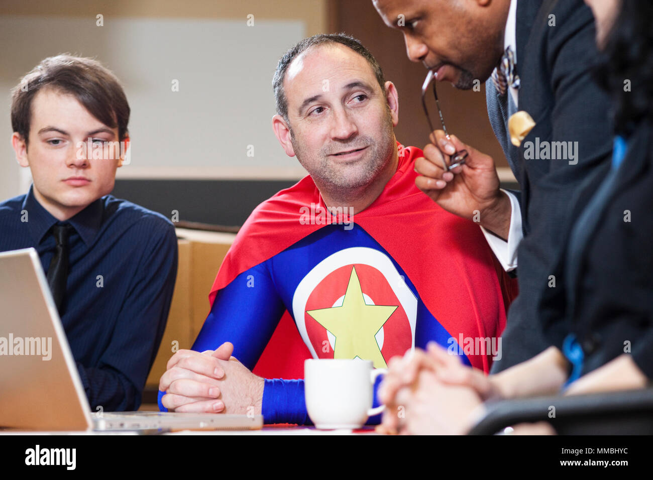 Un bureau de race blanche d'âge moyen super héros lors d'une réunion avec son personnel. Banque D'Images