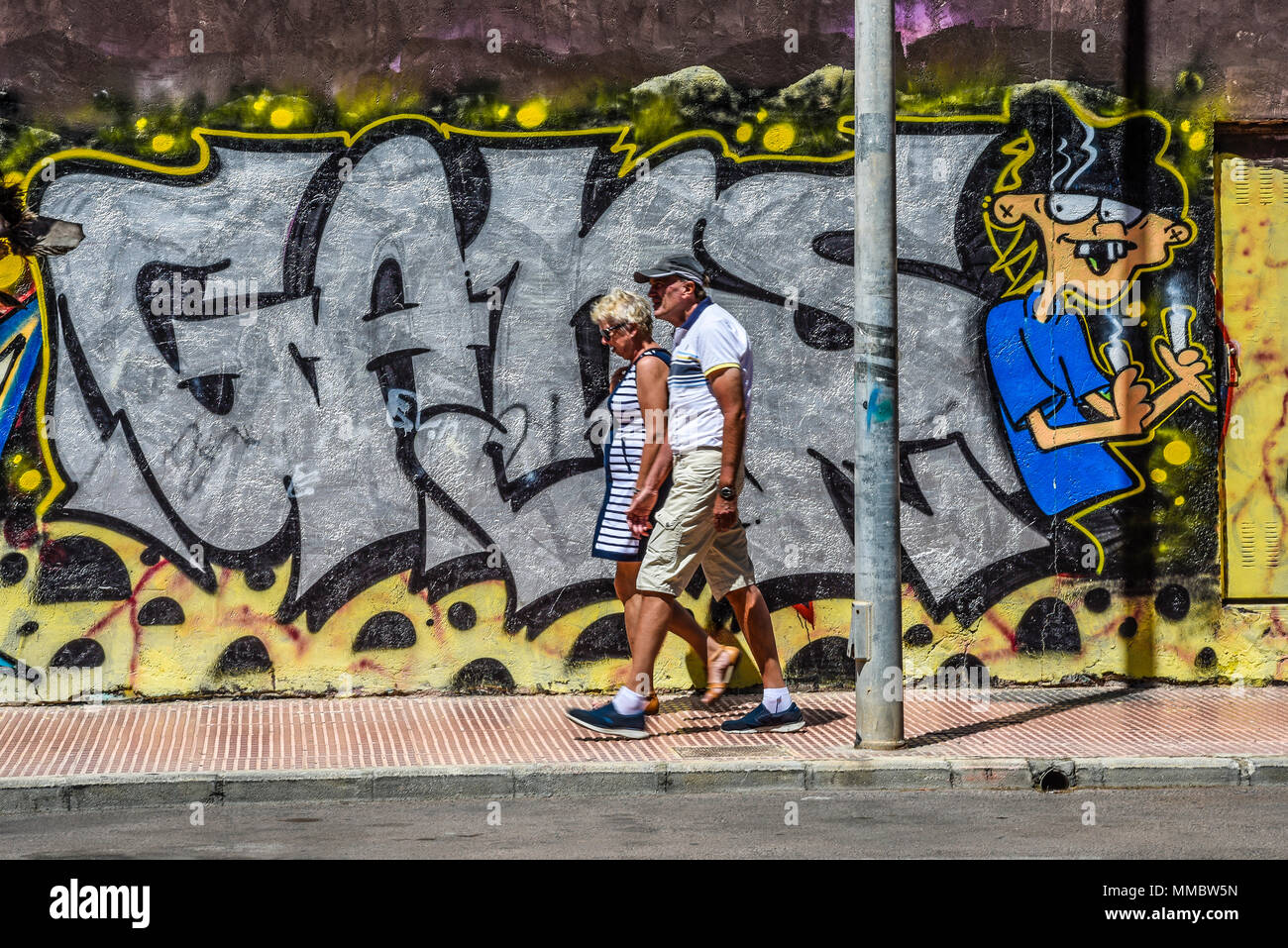 Graffitis sur un mur à Guardamar del Segura, Espagne. Costa Blanca. Yeux suivant les secoueurs. Couple senior marchant Banque D'Images