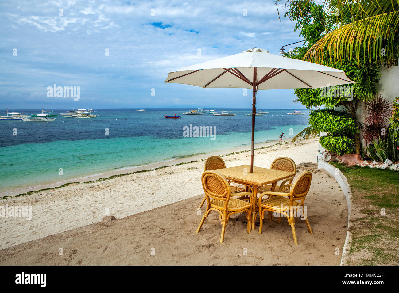 Une table de pique-nique sur la plage avec parasol mis en place pour les touristes de profiter d'une journée à Alona Beach, l'île de Panglao, Philippines. Banque D'Images