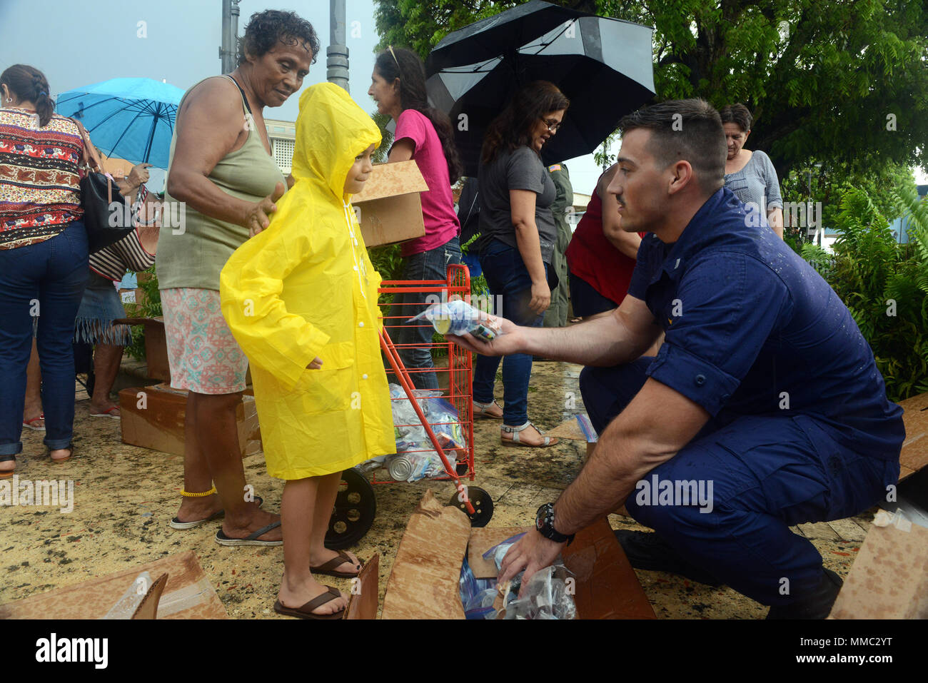 Le lieutenant J.G. Lucas Taylor, un pilote de la Garde côtière à Air Station Borinquen, Puerto Rico, fournit la nourriture et de l'eau à une jeune fille à Moca, Porto Rico, le 9 octobre 2017. La Garde côtière et les organismes partenaires ont été la prestation de l'Agence fédérale de gestion des urgences des fournitures à Porto Rico dans l'ensemble de personnes qui ont été touchées par l'Ouragan Maria. U.S. Coast Guard photo de Maître de 3e classe David Micallef Banque D'Images