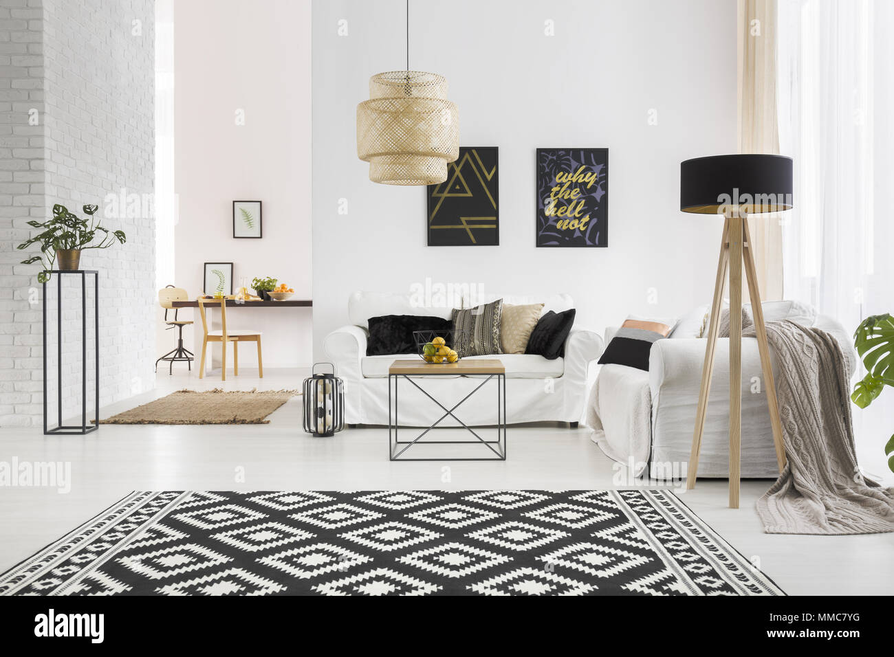 Appartement avec mur de briques blanches, canapé, table et tapis motif Banque D'Images