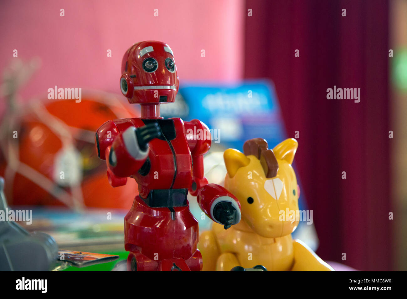 Une paire de jouets pour enfants en plastique coloré un robot et un petit  cheval ou licorne le rouge et jaune à côté de l'autre à la vente à un  village anglais