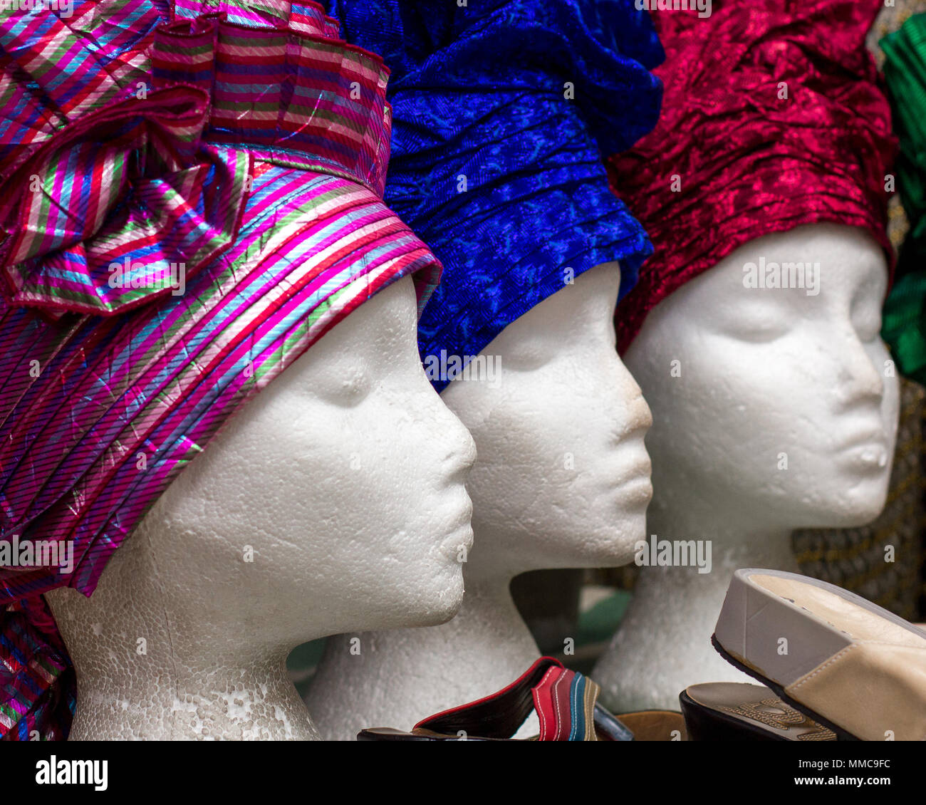 Un trio de female mannequin tête dans un Brixton, Londres, Royaume-Uni, vitrine affichage, portant des chapeaux de style africain, femme coiffures, coiffures de tissu coloré Banque D'Images