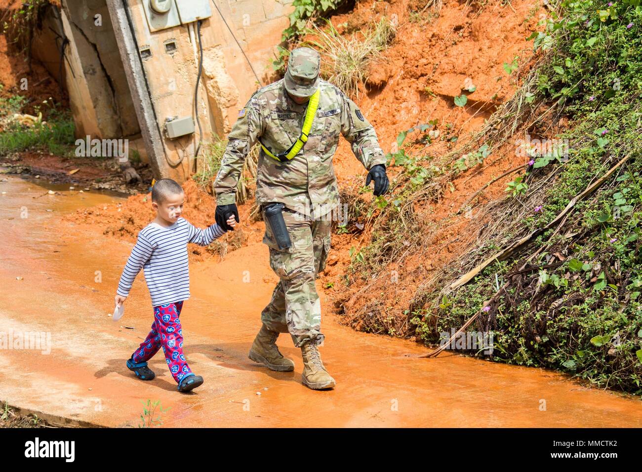 Spec. Leomar paredes de la Garde nationale de Porto Rico prend une pause de nettoyer les routes de passer quelques minutes avec un jeune garçon qui vivait dans les environs de Cayey, Puerto Rico. Paredes est un soldat dans le 190e bataillon du génie, qui a été attribué à dégager des routes à la suite de l'Ouragan Maria. Le bataillon travaille avec des soldats de la Garde nationale de Caroline du Sud pour rendre les routes plus accessible. (36) Maj photo Randall Stillinger Banque D'Images